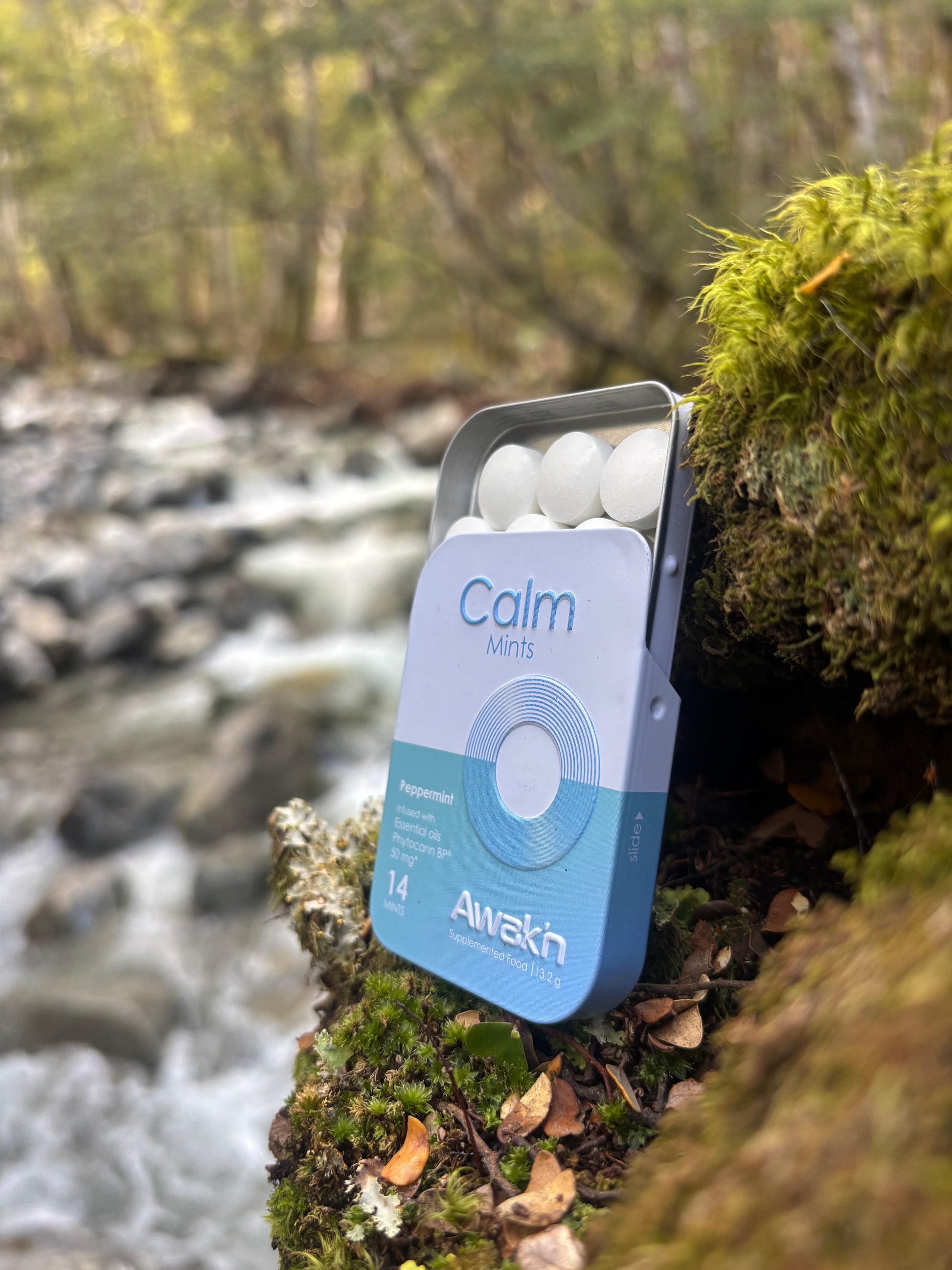 Calm Mints packaging by Awak'n in a natural setting with a stream and trees.